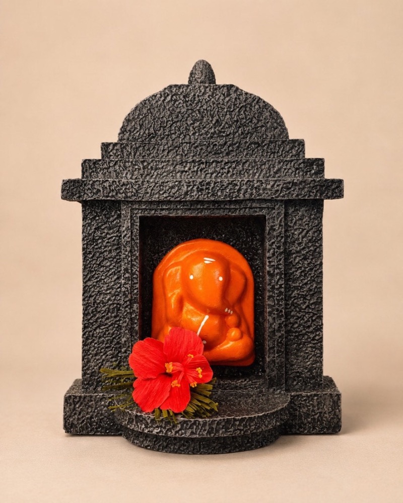 The painted terracotta Ganesha seated in his stone-finish fibreglass temple, seen from the front.